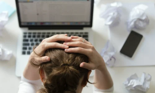 portrait-woman-grabbing-head-desk-near-laptop
